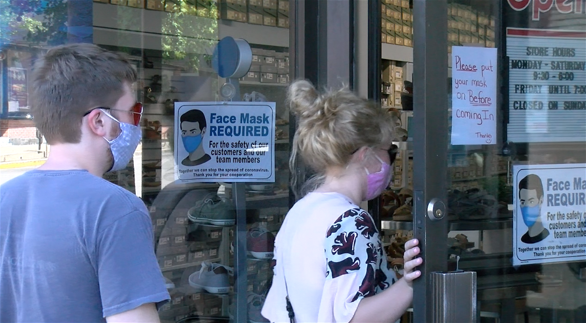 Customers wearing masks walk into a downtown Columbia business 