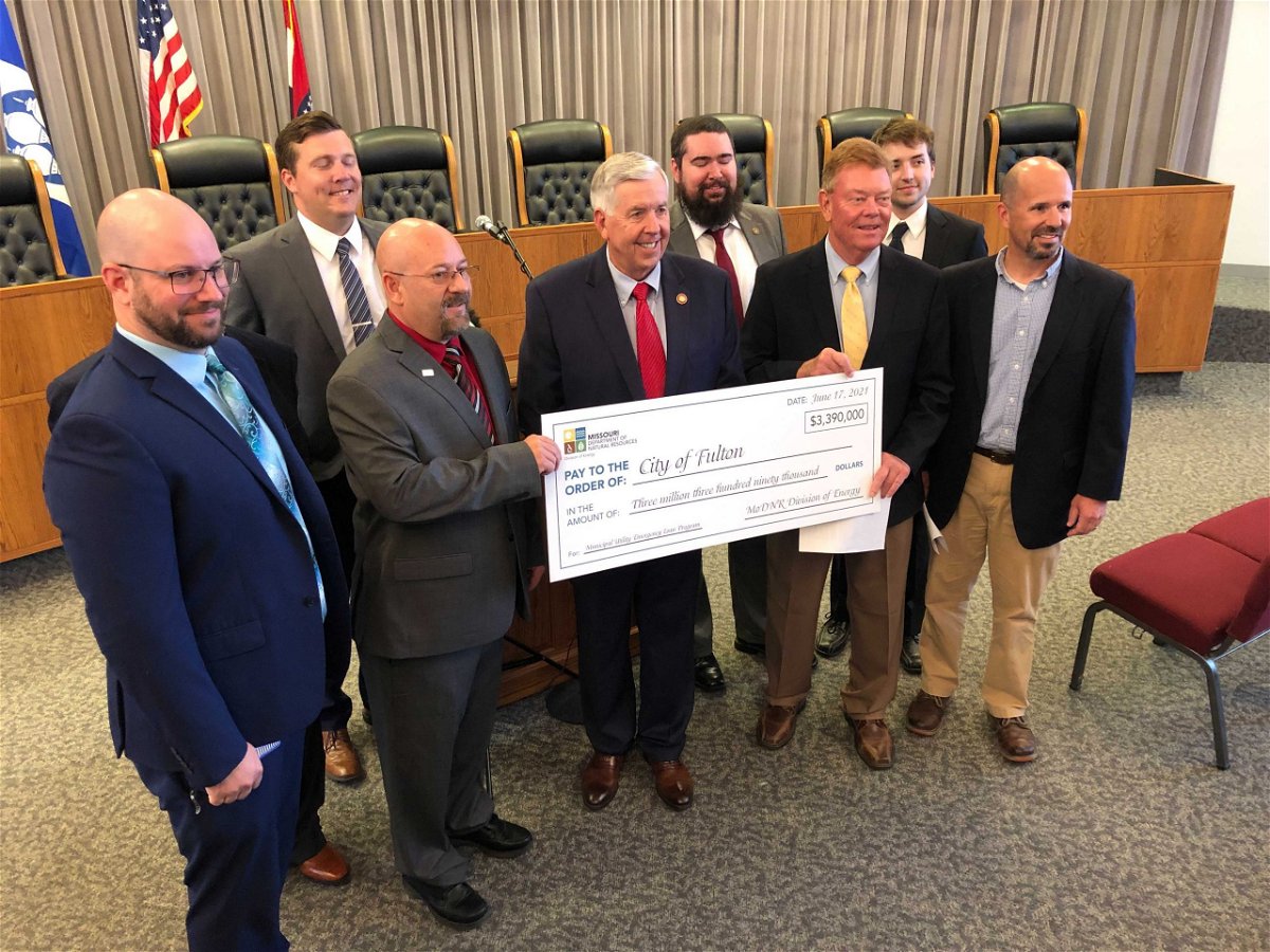 Gov. Mike Parson, center, presents a check to the City of Fulton for a loan to cover energy costs incurred during a February cold snap Tuesday, June 29, 2021.
