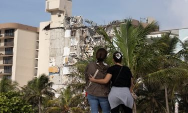 Maria Fernanda Martinez and Mariana Cordeiro look on as search and rescue operations continue at the site of the partially collapsed 12-story condo building on Friday in Surfside