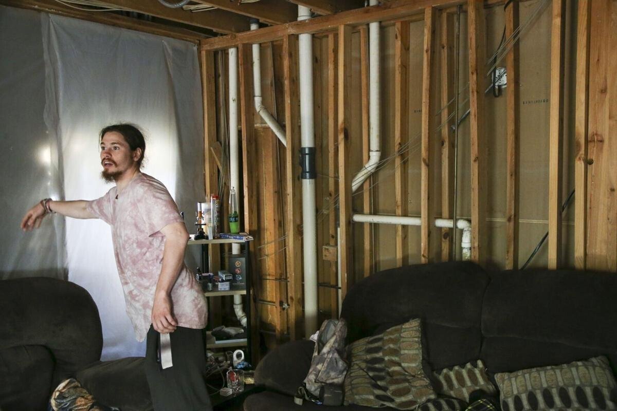 <i>Tulsa World</i><br/>Steven Bell points toward a plastic covering in his living room at Vista Shadow Mountain Apartments. Bell has been living without a ceiling