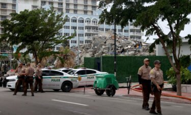 Miami-Dade police officers helping with the search and rescue stand near the completely collapsed 12-story Champlain Towers South on July 6