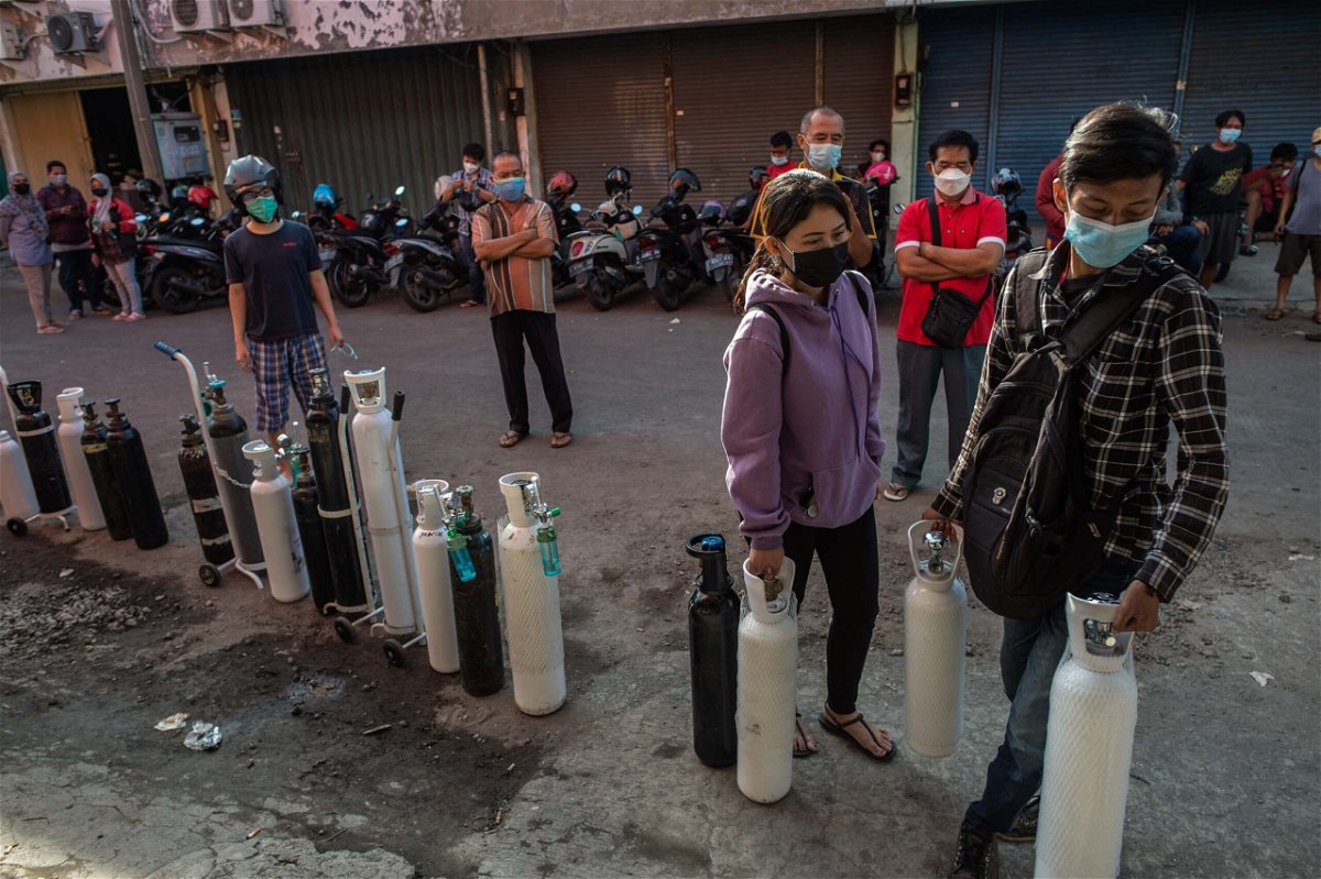 <i>JUNI KRISWANTO/AFP/Getty Images</i><br/>Residents queue up to get oxygen tanks refilled at a refilling station in Surabaya on July 15.