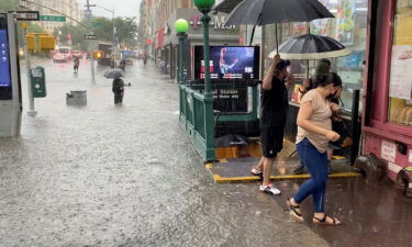 A person wades through floodwater as people exit the 157th St. metro station in New York City on July 8.