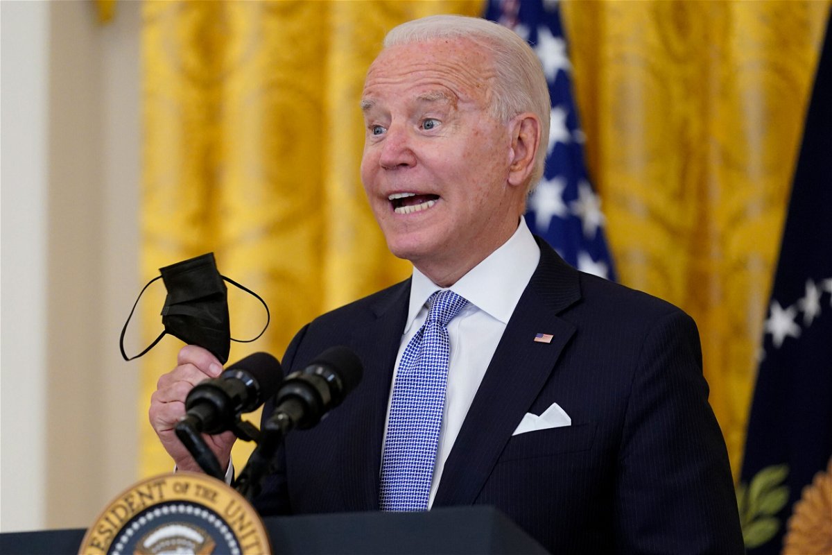 <i>Susan Walsh/AP</i><br/>President Joe Biden holds his face mask as he speaks in the East Room of the White House in Washington