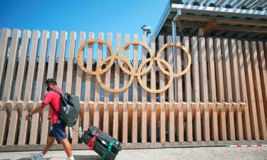 A member of the Mexican delegation walks past Olympic rings at the entrance to Olympic Village. The sports world