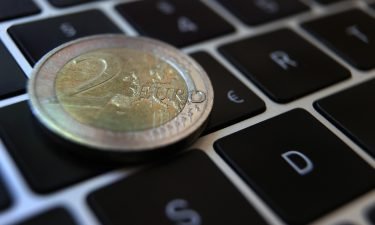 A two-euro coin lies on the keyboard of a laptop next to a euro sign. The European Central Bank is moving ahead with efforts to create a digital version of the euro as the use of cash declines and China ramps up tests of its own e-yuan.