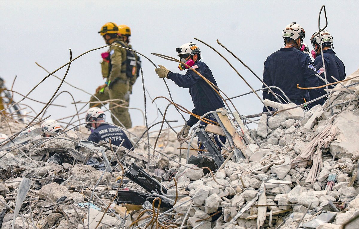 <i>Al Diaz/AP</i><br/>Search and rescue team members dig through the debris field of the 12-story oceanfront condo