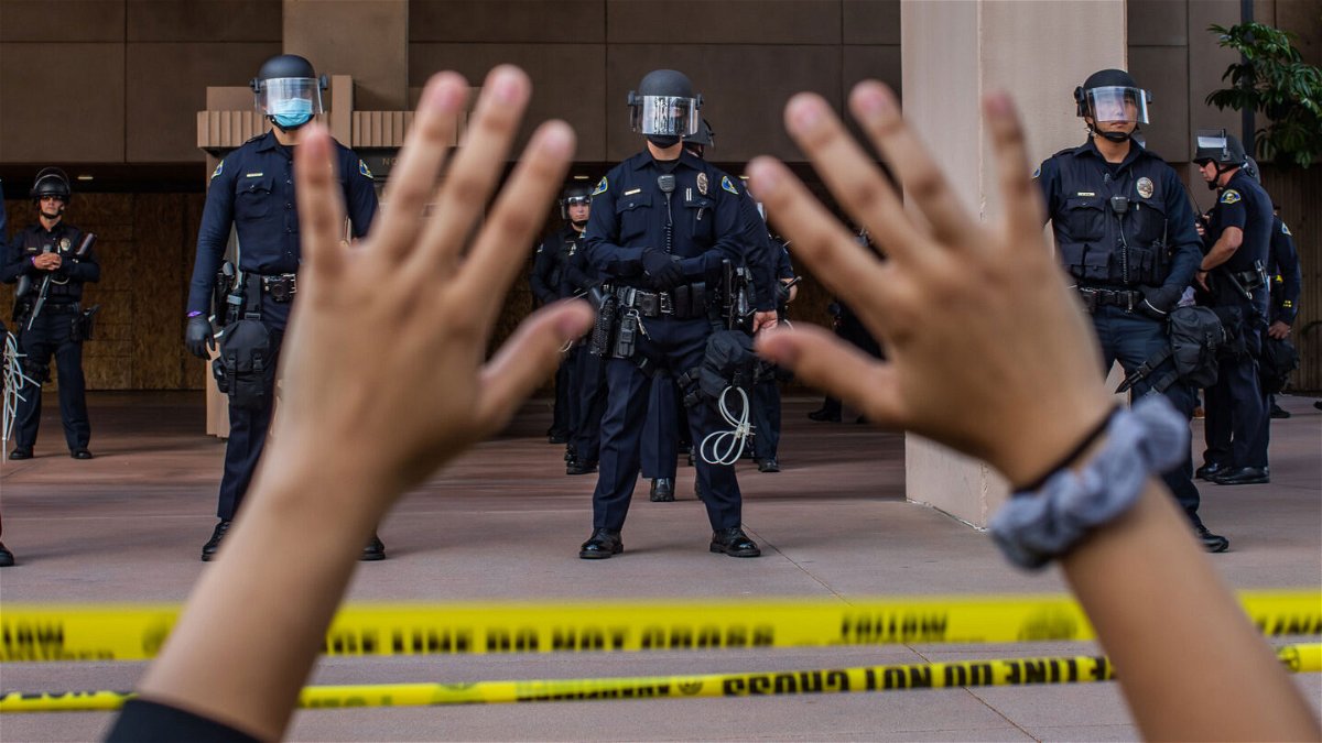 <i>APU GOMES/AFP/Getty Images</i><br/>A demonstrator holds her hands up while she kneels in front of the police at the Anaheim City Hall last year in Anaheim