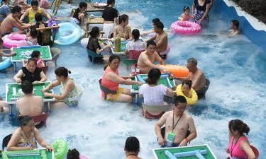 Tourists play mahjong in water to escape summer heat at a water park on July 10