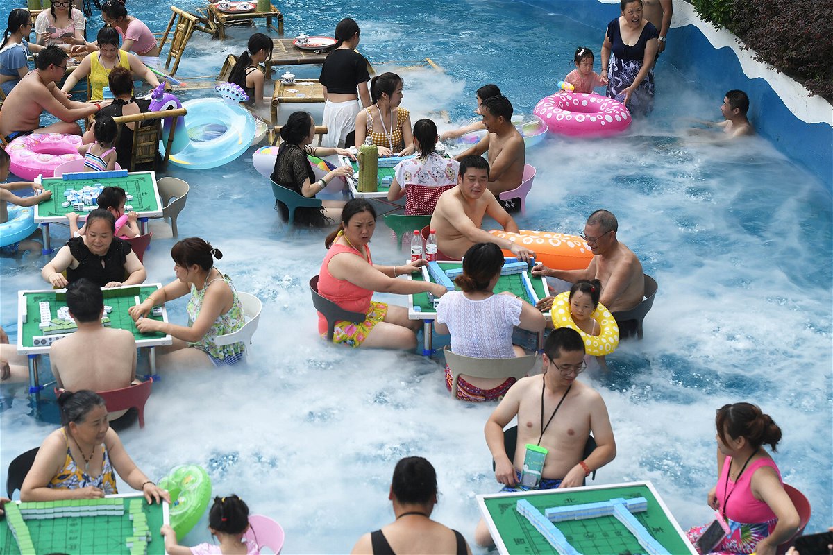 <i>Chen Chao/China News Service/Getty Images</i><br/>Tourists play mahjong in water to escape summer heat at a water park on July 10