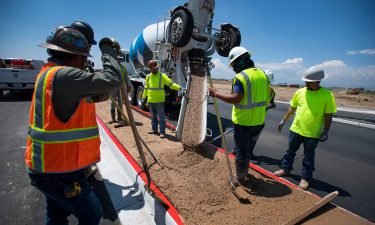 Construction workers pour concrete into a median along Larimer County Road 5 near Windsor