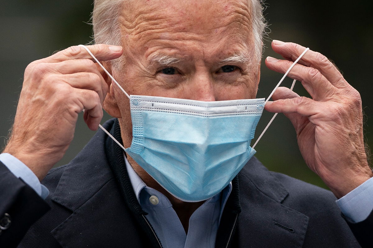 <i>Drew Angerer/Getty Images</i><br/>Then-Democratic presidential nominee Joe Biden puts on a face mask while speaking to reporters at a voter mobilization center on October 26