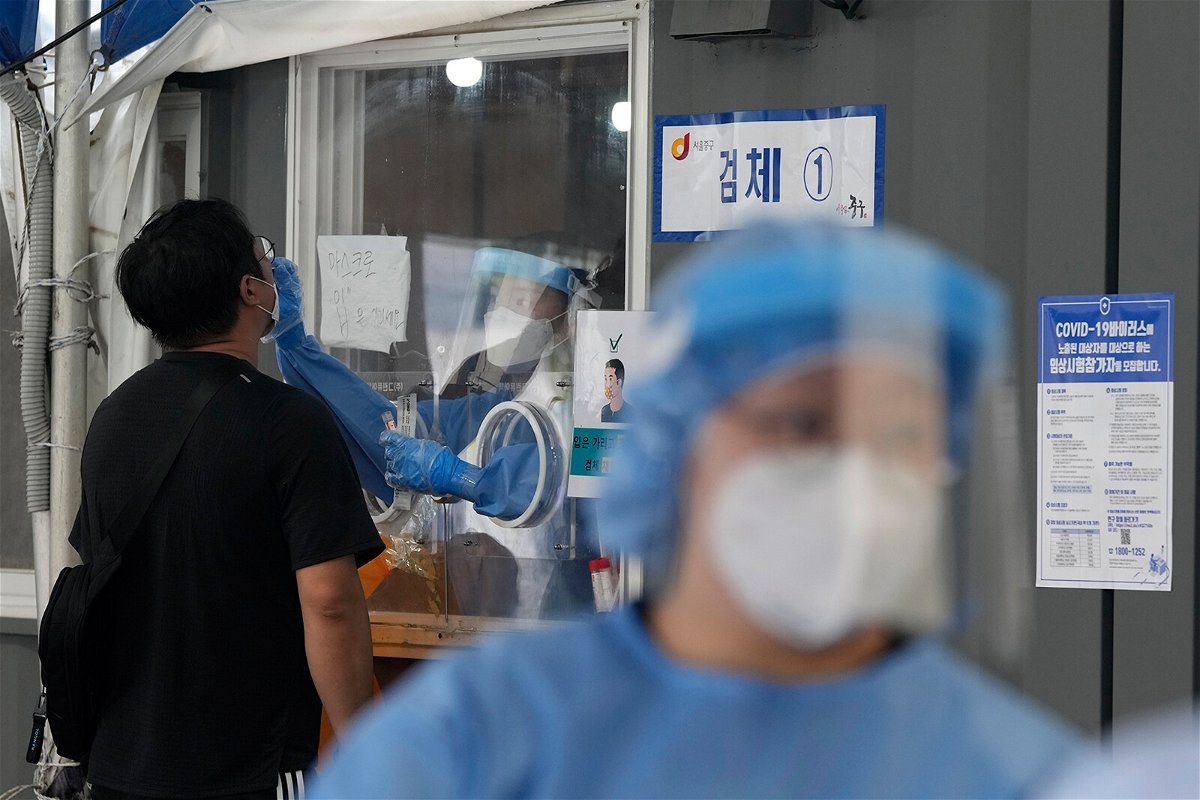 <i>Ahn Young-joon/AP</i><br/>Lockdowns toughen in Seoul and Sydney as Delta variant Covid-19 outbreaks grow. A medical worker in a booth takes a nasal sample from a man during Covid-19 testing at its site in Seoul on Thursday.