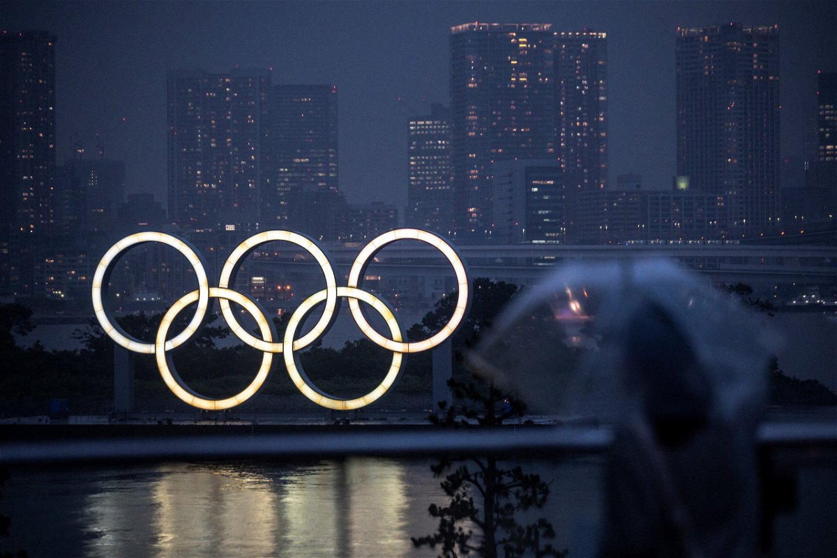 <i>CHARLY TRIBALLEAU/AFP/Getty Images</i><br/>A woman walks past the Olympic Rings lit up at dusk in the rain