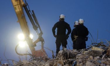 Search and rescue workers oversee an excavator dig through the rubble of the collapsed Champlain Towers South condo building.