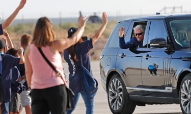 Virgin Galactic founder Richard Branson waves to school children while heading to board the rocket plane that will fly him to space from Spaceport America near Truth or Consequences
