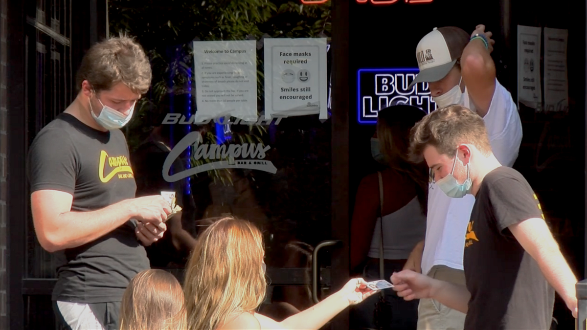 Patrons show IDs to masked staff members outside Campus Bar and Grill in Columbia on March 4, 2021.