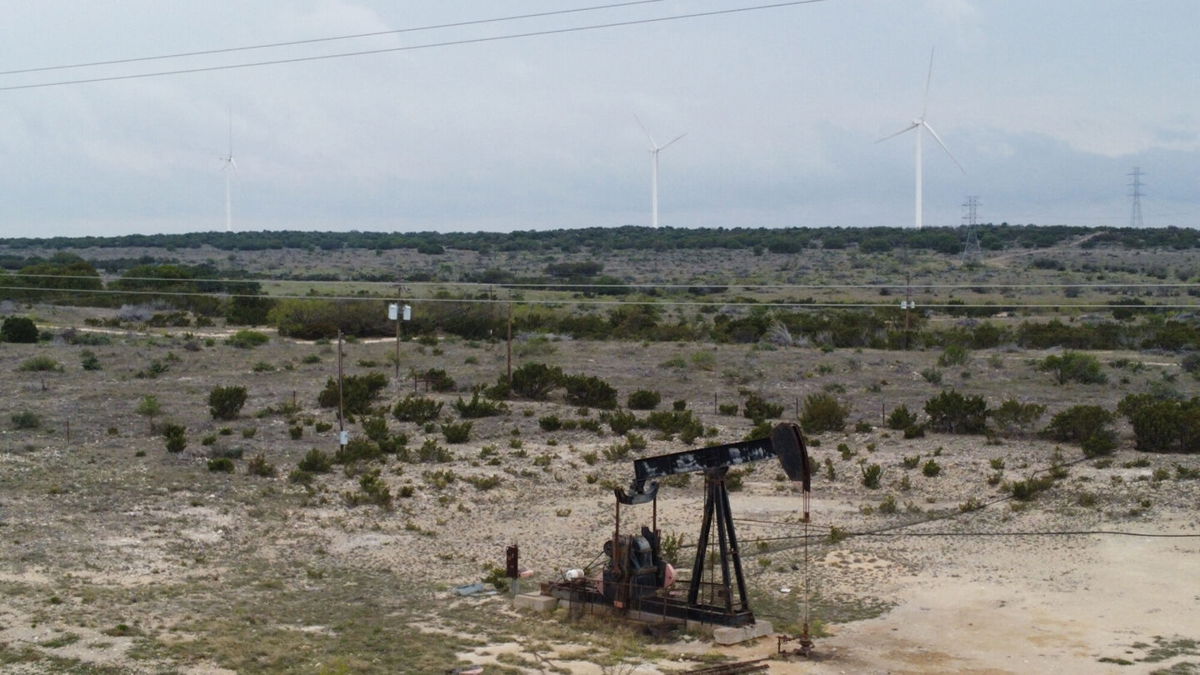 <i>Francois Picard/AFP/Getty Images</i><br/>Blades from wind turbines rotate in a field behind an out-of-use oil pumpjack on April 16 near Eldorado