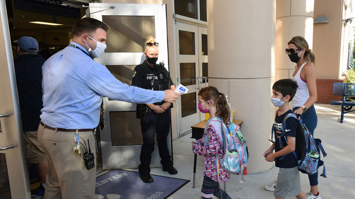 <i>Paul Hennessy/SOPA Images/Getty Images</i><br/>Judge John Cooper ruled Friday against Florida Gov. Ron DeSantis' ban on mask mandates in schools. Principal Nathan Hay checks students' temperatures as they arrive at Baldwin Park Elementary School in Orlando
