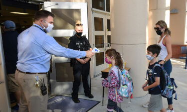Judge John Cooper ruled Friday against Florida Gov. Ron DeSantis' ban on mask mandates in schools. Principal Nathan Hay checks students' temperatures as they arrive at Baldwin Park Elementary School in Orlando