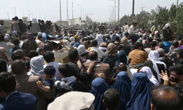 Afghans gather on a roadside near the military part of the airport in Kabul on August 20