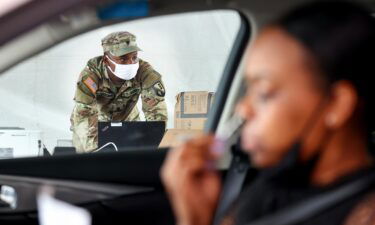 A driver administers a self-collected nasal swab at a Covid-19 drive-through testing site operated by the National Guard on August 11