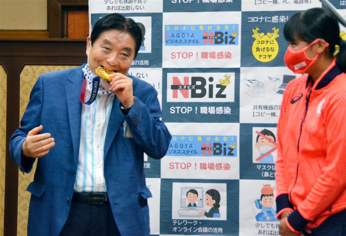 <i>Kyodo News/AP</i><br/>Nagoya Mayor Takashi Kawamura bites the Olympic gold medal of Miu Goto.