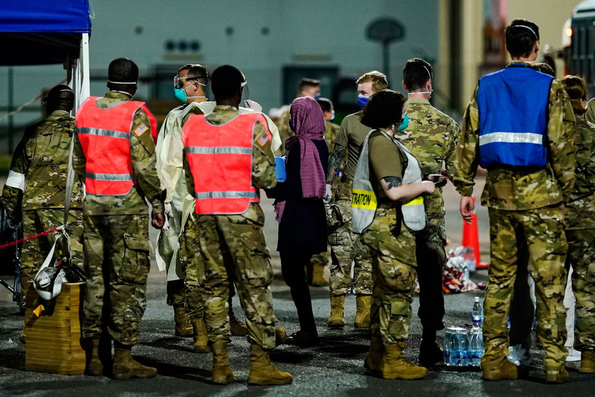 <i>Uwe Anspach/picture-alliance/dpa/AP</i><br/>People flown out of Afghanistan leave a transport bus at Ramstein Air Base and are met by soldiers and helpers.