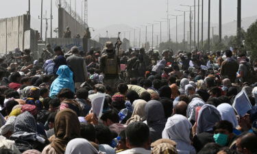 Afghans gather on a roadside near the military part of the airport in Kabul on August 20