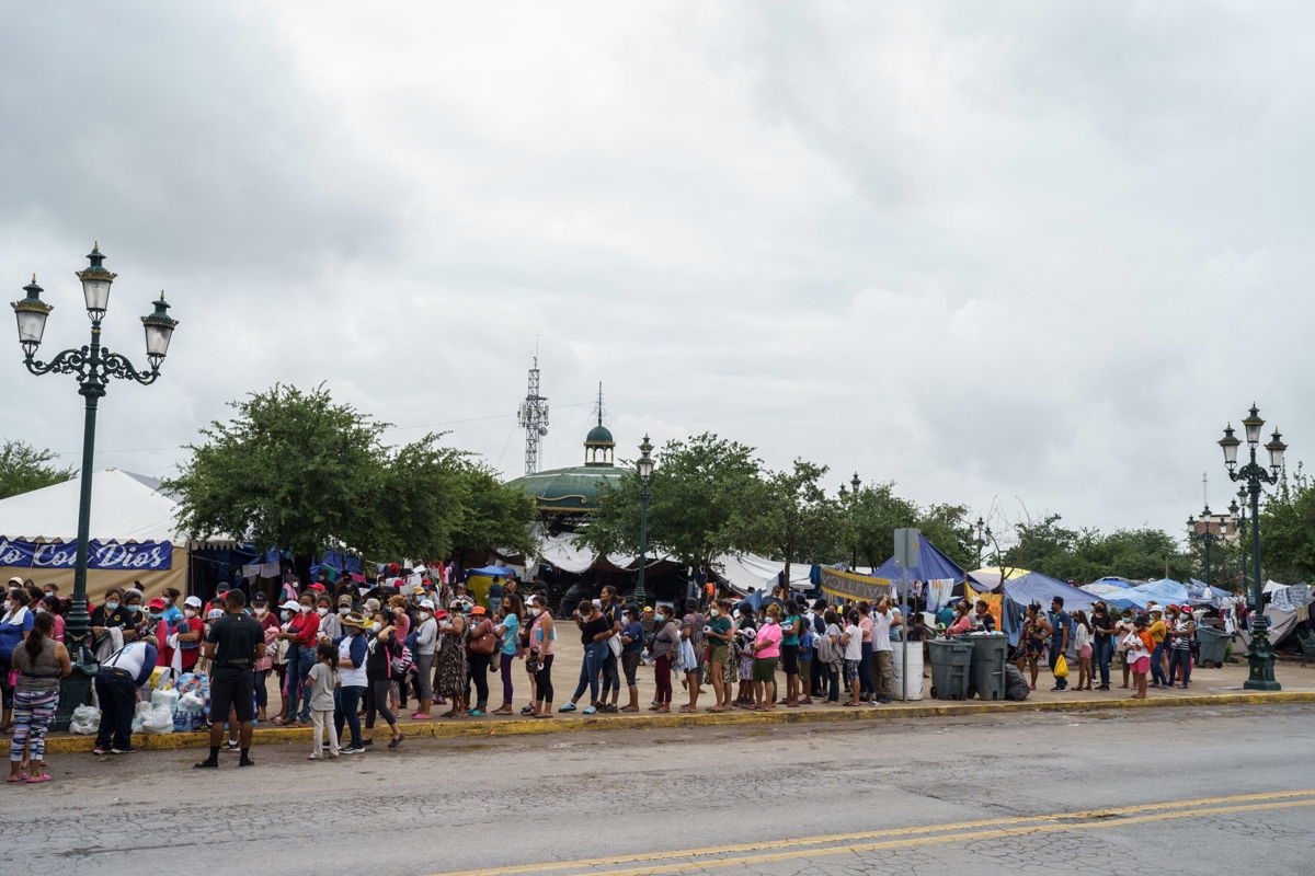 <i>Paul  Ratje/AFP/Getty Images</i><br/>A Federal appeals court Thursday ordered the Biden administration to reinstate former President Donald Trump's 'remain in Mexico' policy.  Migrants here line up for food in a camp in Reynosa