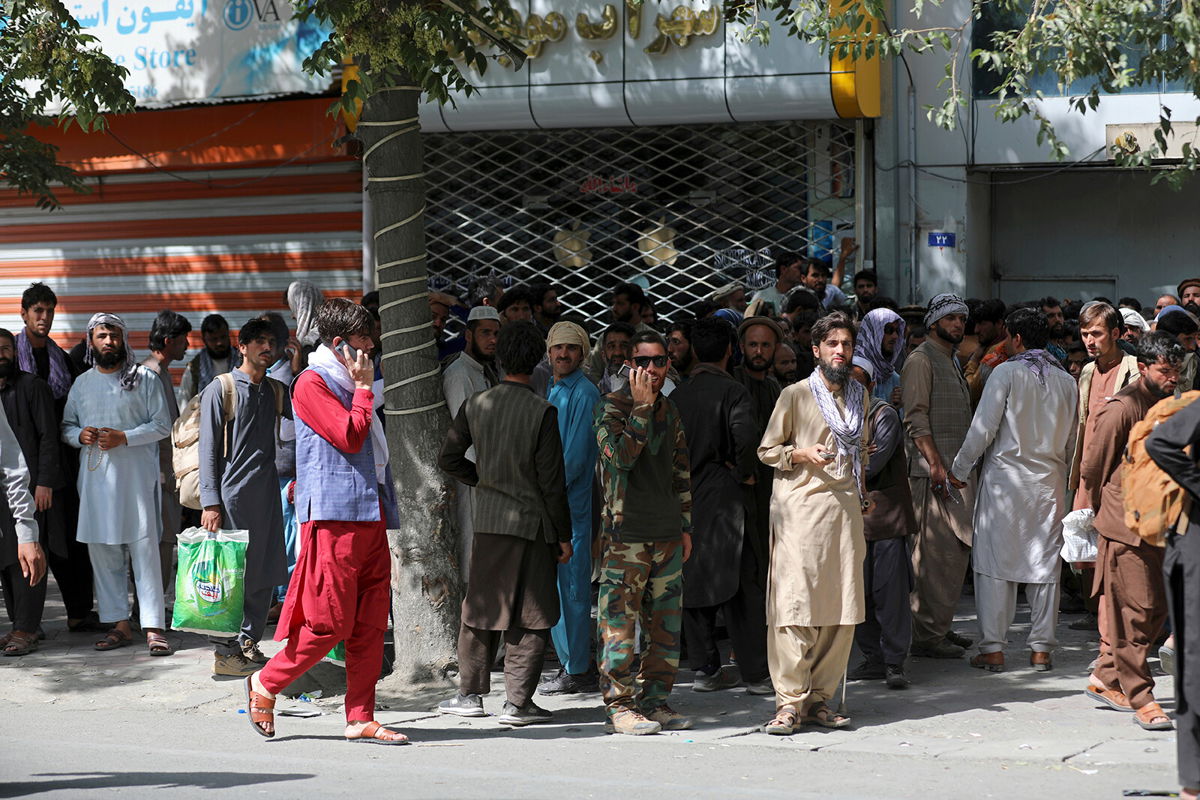 <i>Rahmat Gul/AP</i><br/>Afghans wait in long lines for hours to withdraw money