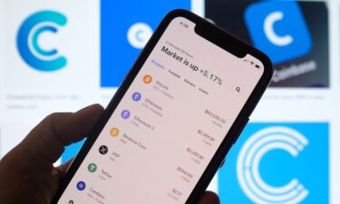 This illustration photo shows the Coinbase logo in the background as a person checks cryptocurrencies prizes on a smartphone in Los Angeles on April 13. Members of the cryptocurrency world are donating to crypto-focused organizations