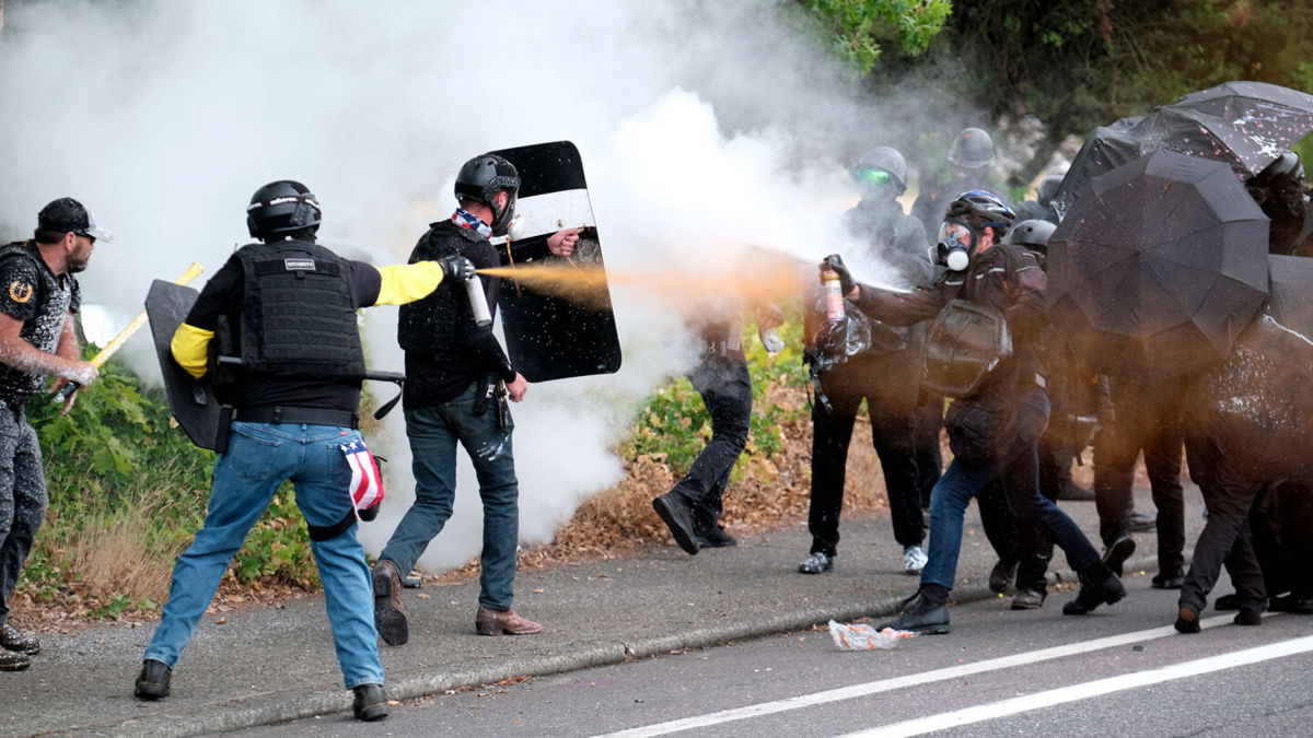 <i>Alex Milan Tracy/AP</i><br/>Members of the far-right group Proud Boys and counterprotesters spray mace at each other during clashes on Sunday in northeast Portland.