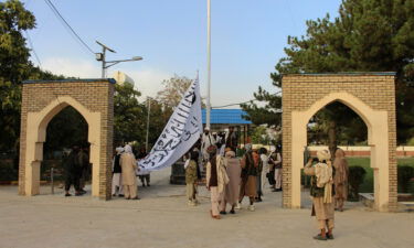 Taliban fighters raise their flag at the provincial governor's house in Ghazni