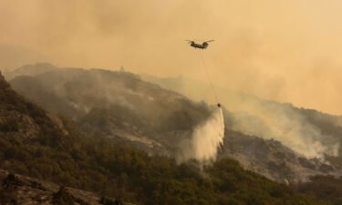 A Boeing CH-47 Chinook firefighting helicopter carries water to drop on the fire as smoke rises in the foothills along Generals Highway during a media tour of the KNP Complex fire in the Sequoia National Park near Three Rivers