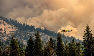 A helicopter flies over Wrights Lake while battling the Caldor Fire in Eldorado National Forest