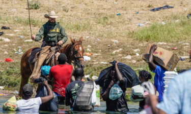 A United States Border Patrol agent on horseback uses the reins as he tries to stop Haitian migrants from entering an encampment. The DHS has since temporarily suspended the use of horse patrol.