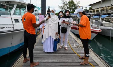 Passengers scan an app to monitor their health status before boarding a yacht in Langkawi