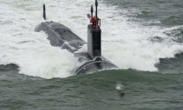 A dolphins swims in front of Navy's newest submarine