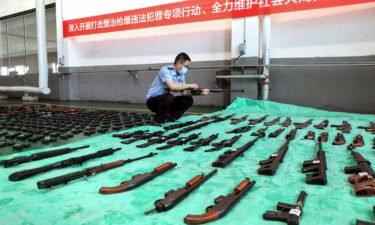 A police officer inspects confiscated illegal guns slated for destruction at an incineration facility in Shenyang