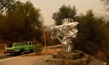 A US Forest Service vehicle drives past the Sequoia National Park historic park entrance sign wrapped in fire resistant foil along Generals Highway during a media tour of the KNP Complex fire in the Sequoia National Park near Three Rivers