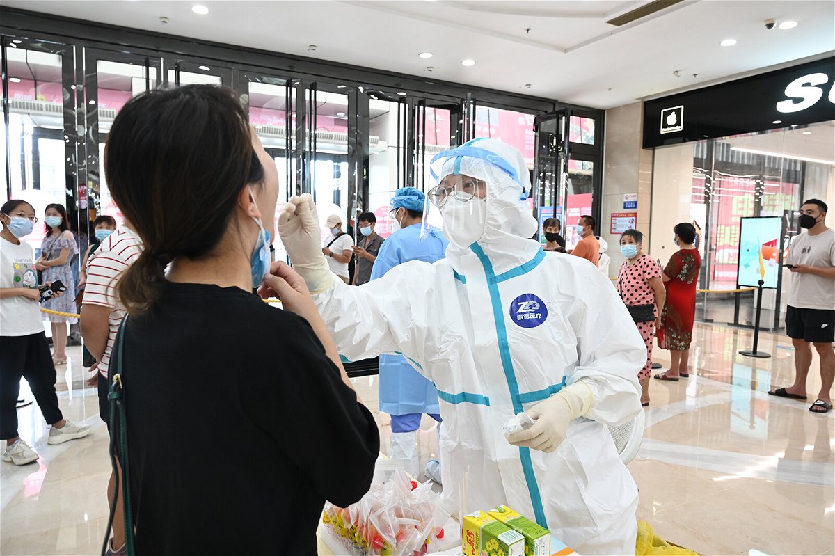 <i>Visual China Group/Getty Images</i><br/>China's strict 21 day quarantine is under question after a new Covid-19 outbreak emerges. A medical worker here collects a throat swab on September 11