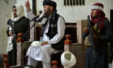 Armed Taliban fighters stand next to a Mullah