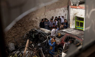 Relatives and neighbors inspect damage in the cramped courtyard of a house in Kabul