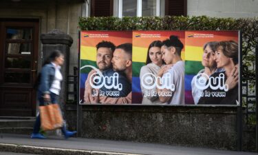 A woman walks past an electoral poster reading in French: "Yes I want it" ahead of a nationwide vote on marriage for all