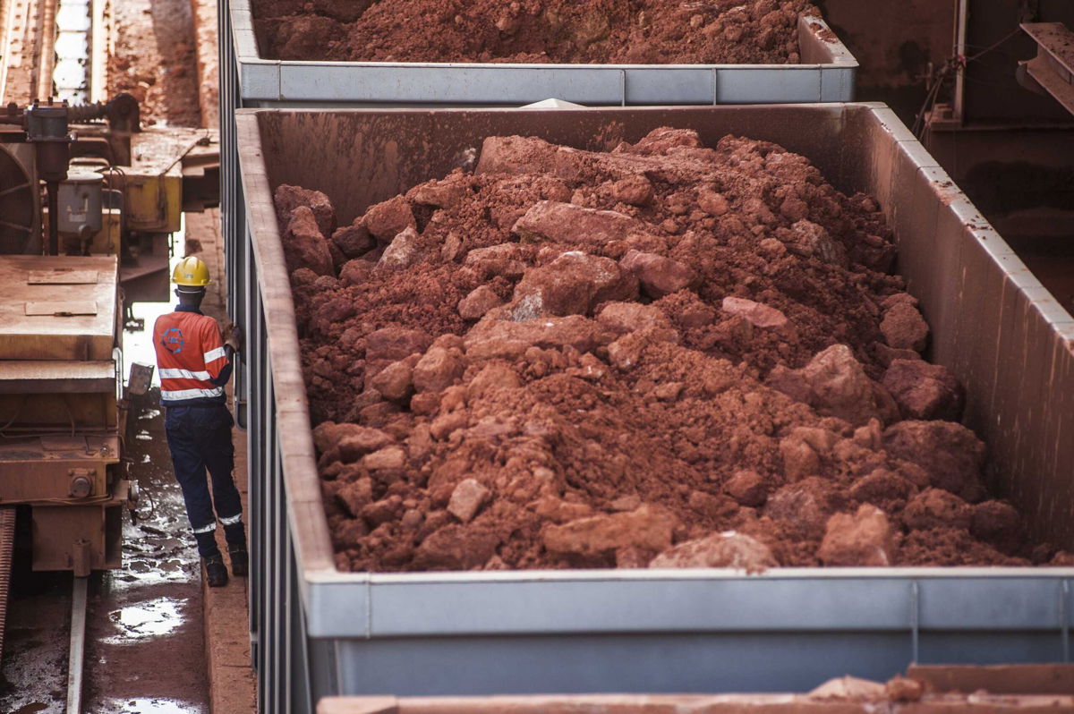 <i>Waldo Swiegers/Bloomberg/Getty Images</i><br/>A worker stands beside railway freight wagons loaded with bauxite