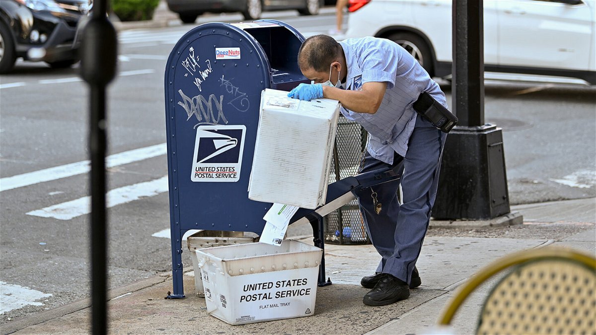 <i>Dia Dipasupil/Getty Images</i><br/>A United States Postal Service (USPS) worker wearing a protective mask and gloves makes his rounds in New York City in 2020.