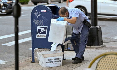 A United States Postal Service (USPS) worker wearing a protective mask and gloves makes his rounds in New York City in 2020.