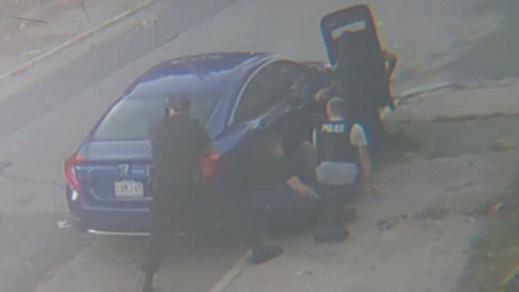 <i>WBZ</i><br/>Police officers take cover behind a car during a standoff  on October 7.