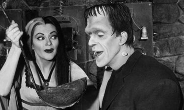 Lily Munster (Yvonne De Carlo) holds a giant ladle for Herman Munster (Fred Gwynne) in an episode of the original "The Munsters."